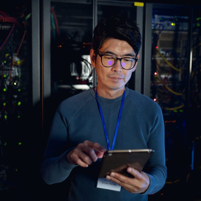 Asian male engineer using digital tablet in computer server room