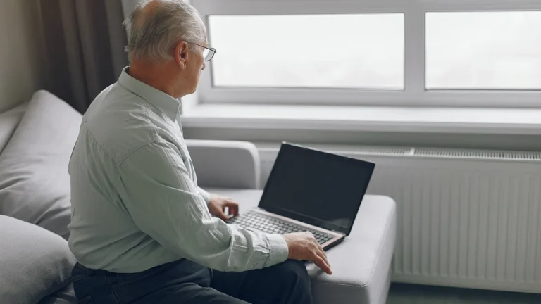 Older man sitting on his sofa at home, using a laptop