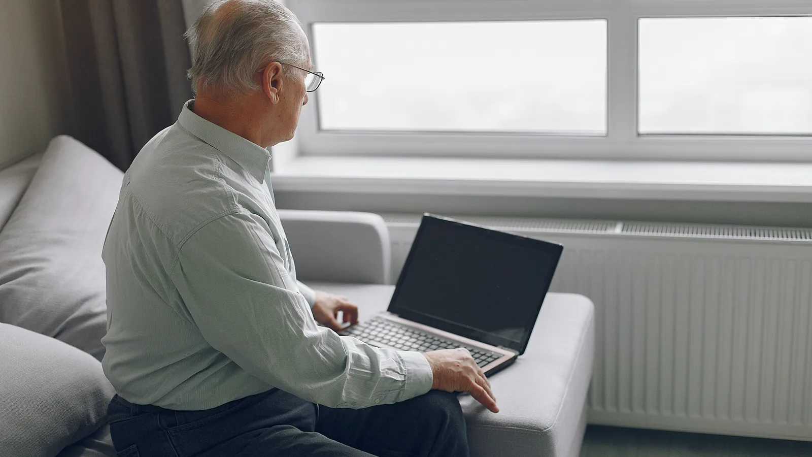 Older man sitting on his sofa at home, using a laptop